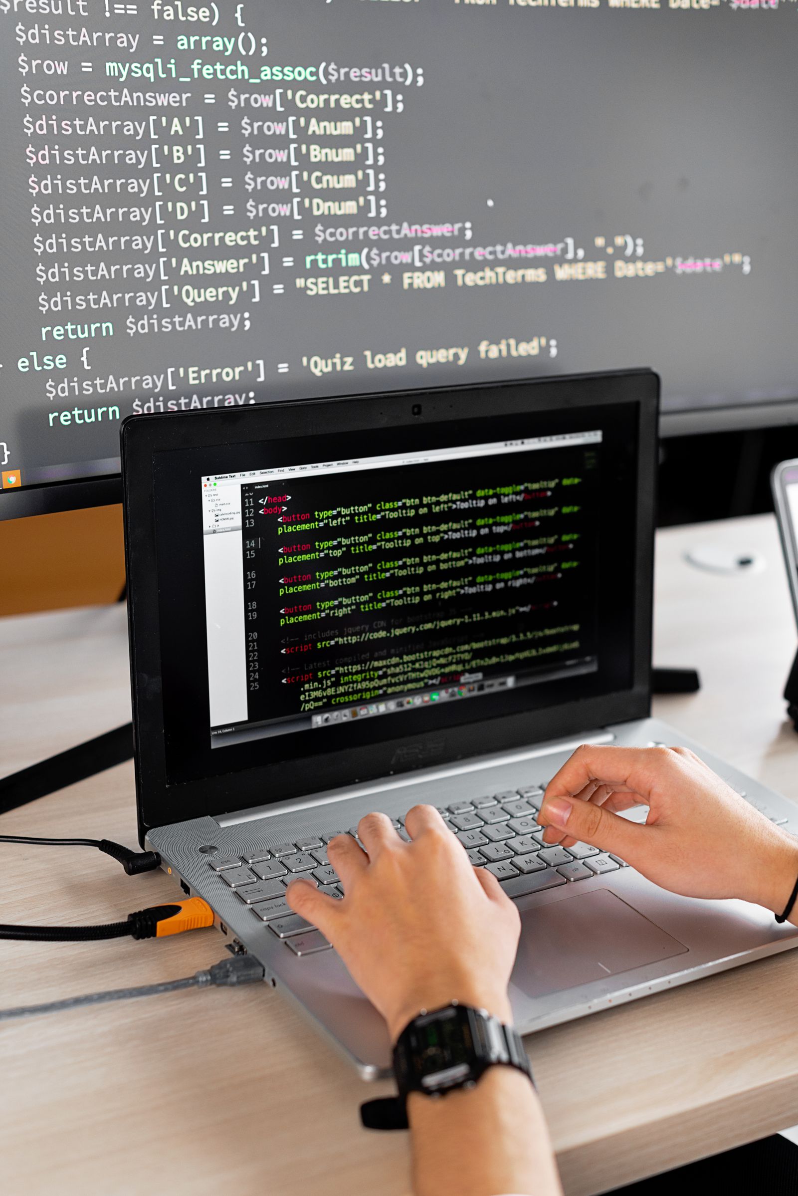 Developer working at a desk with application code displayed on screens